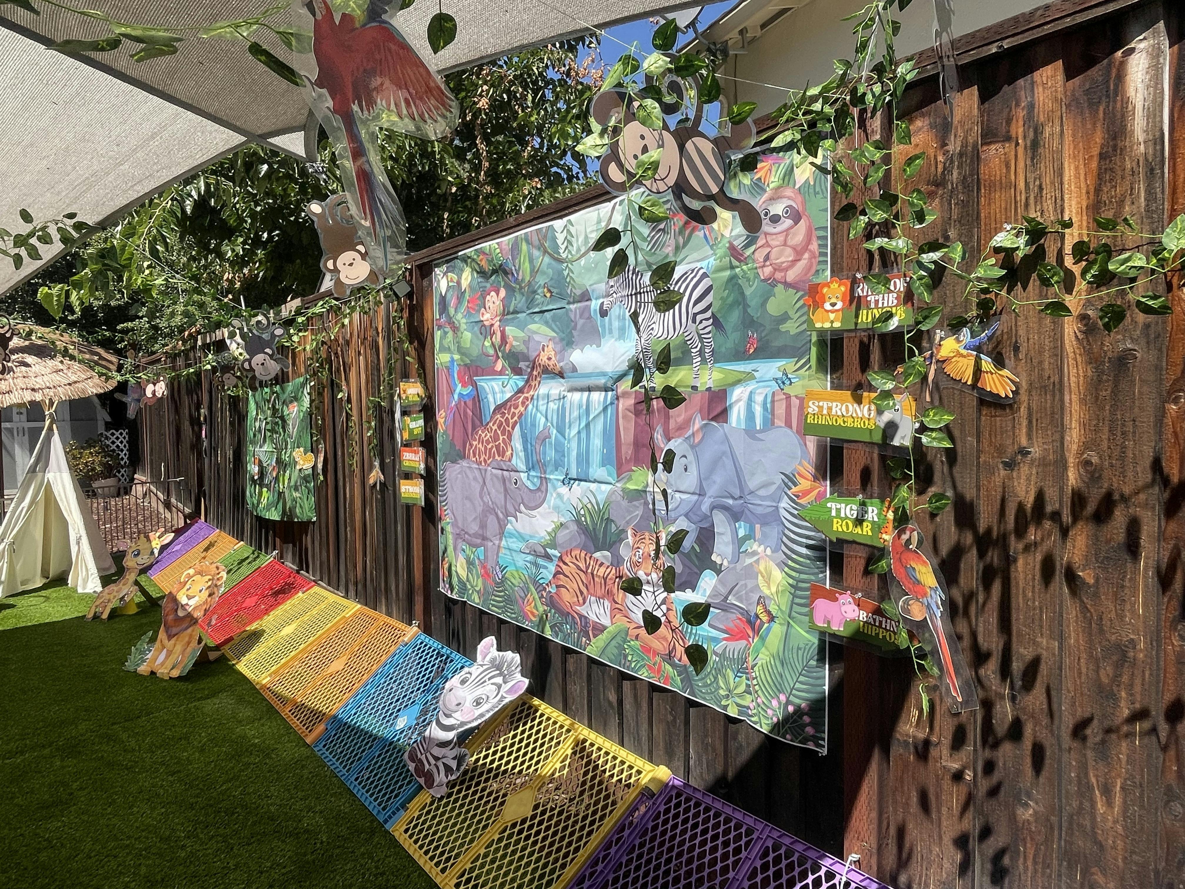Jungle themed party decorations with animal cutouts and a banner on a fence