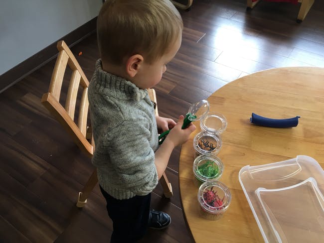 Child looking at small containers with a magnifying glass