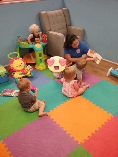 Adult reading to children on a colorful mat