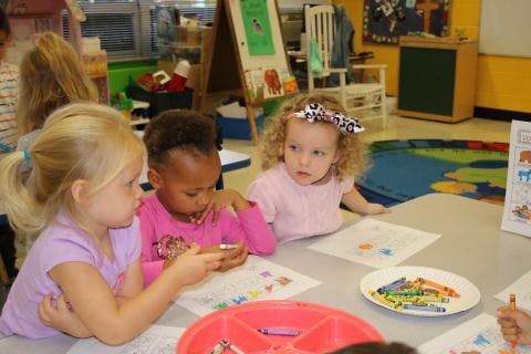 Three children sitting at a table in a classroom
