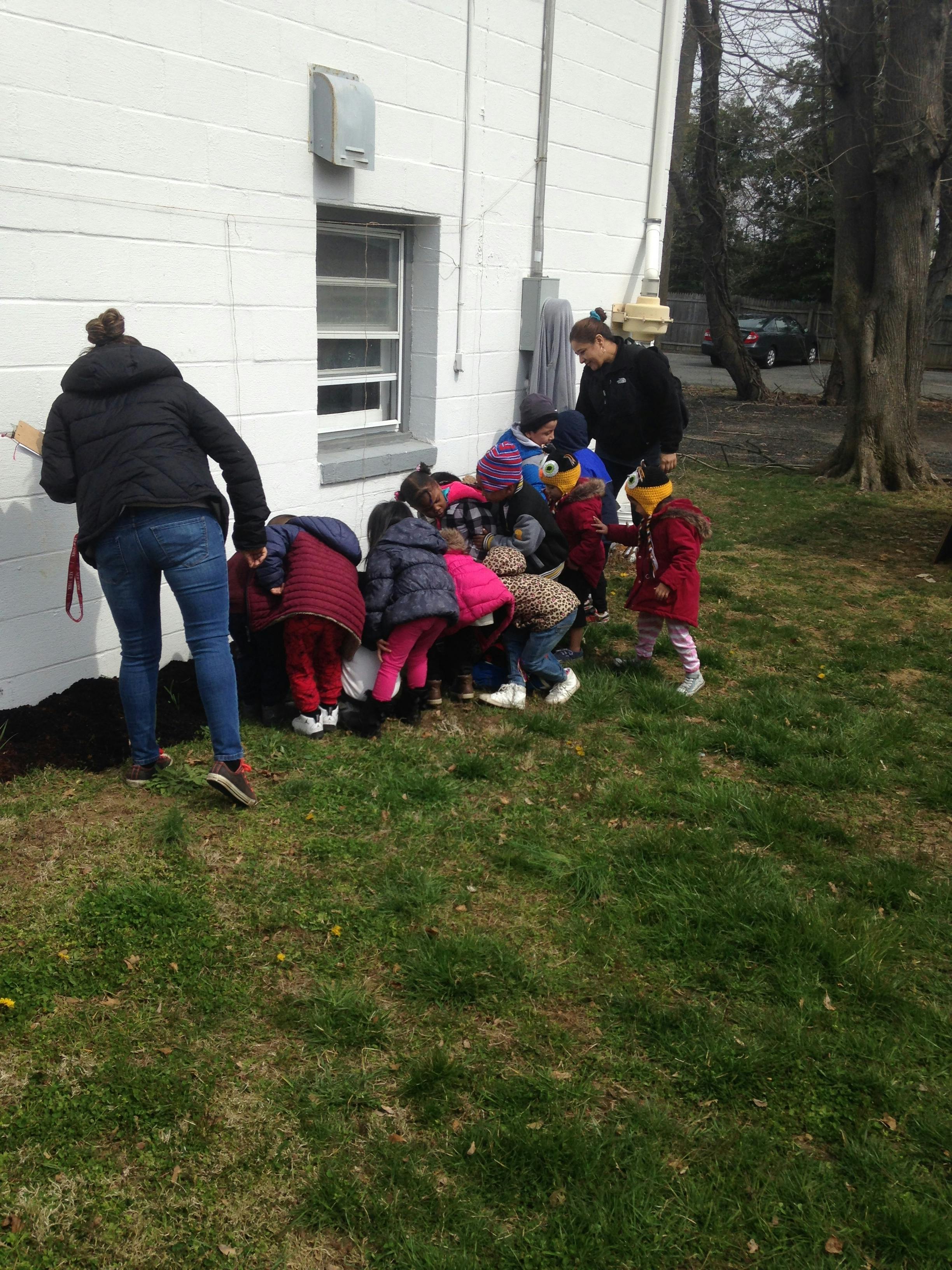 People and children gathered around the side of a building