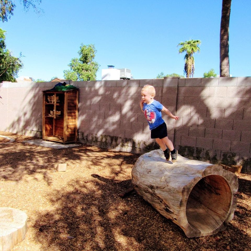 Child jumping on a hollow log