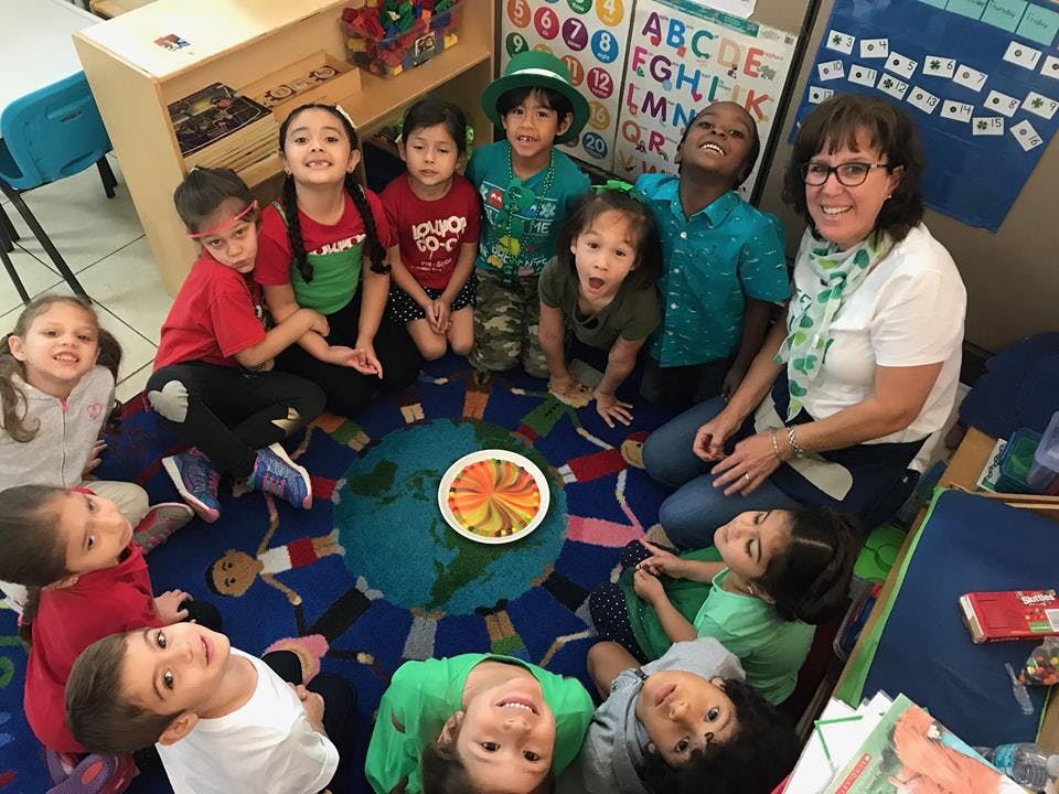 Adult and children sitting in a circle on a rug with a globe design