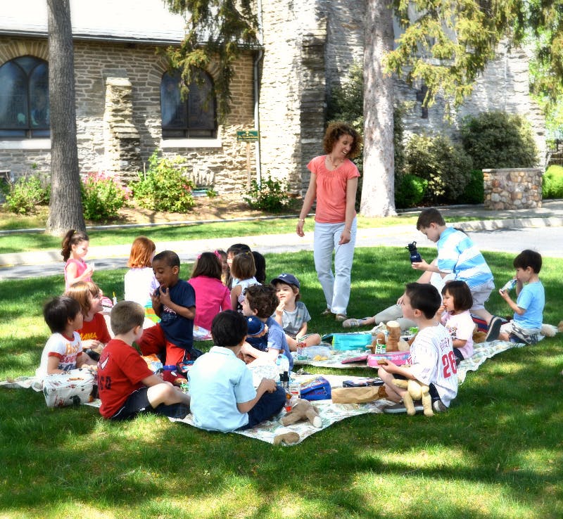 Adult and children sitting on blankets on grass