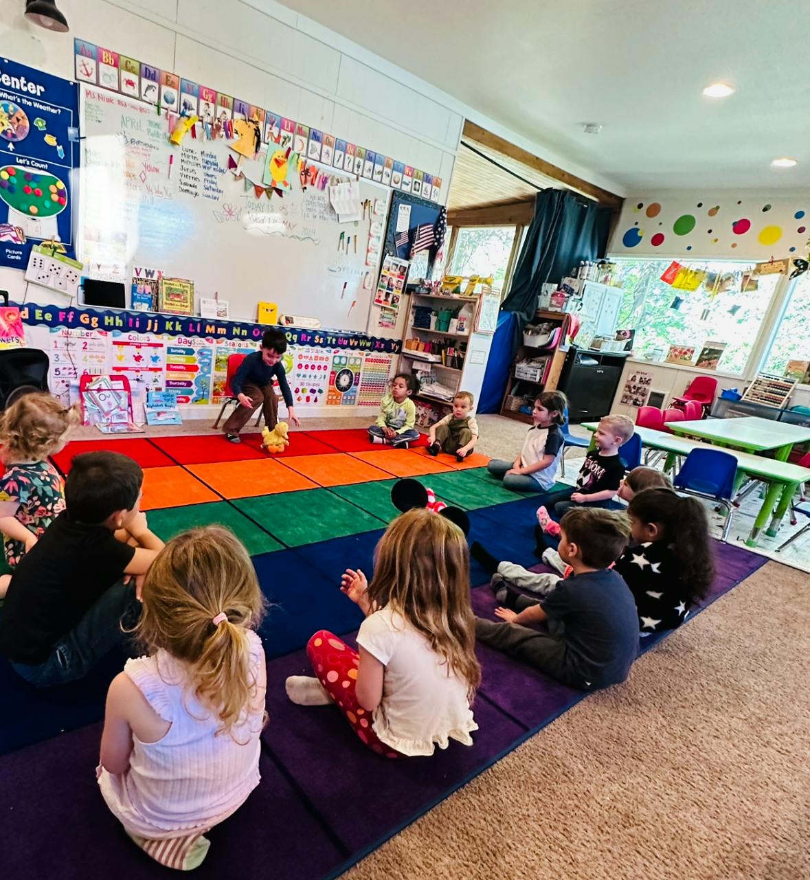 Children sitting on a colorful mat in a classroom
