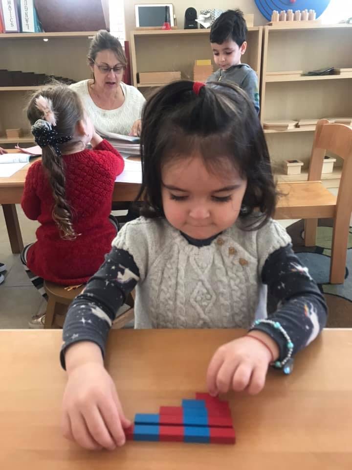 Child playing with red and blue blocks at a table