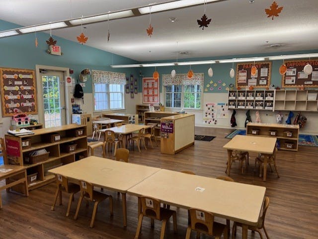 Classroom with small tables and chairs, shelves, and fall leaf decorations