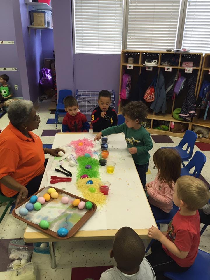 Adult and children at a table with colorful eggs and craft supplies