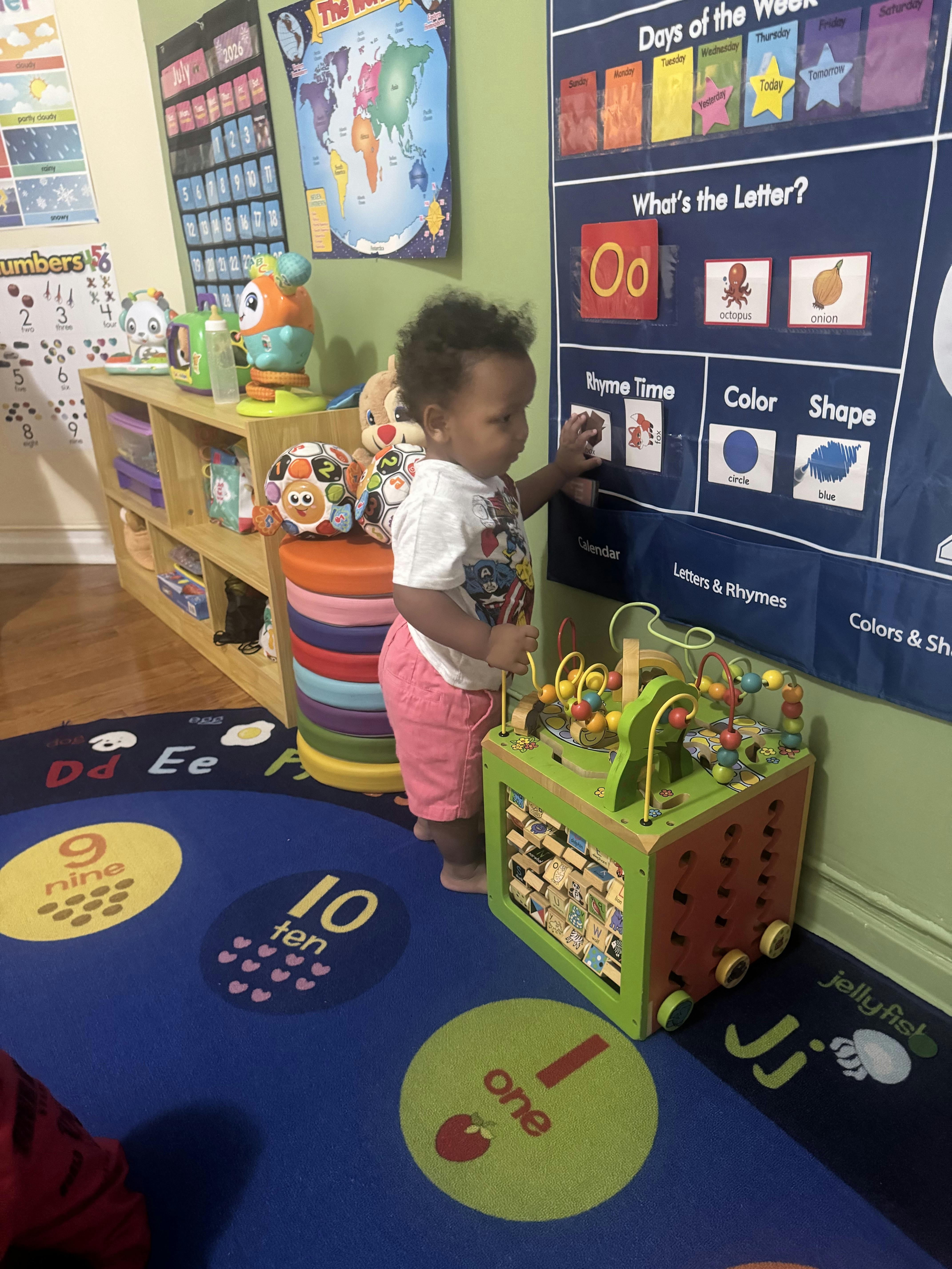 Child playing with a wall learning chart and a bead maze activity cube
