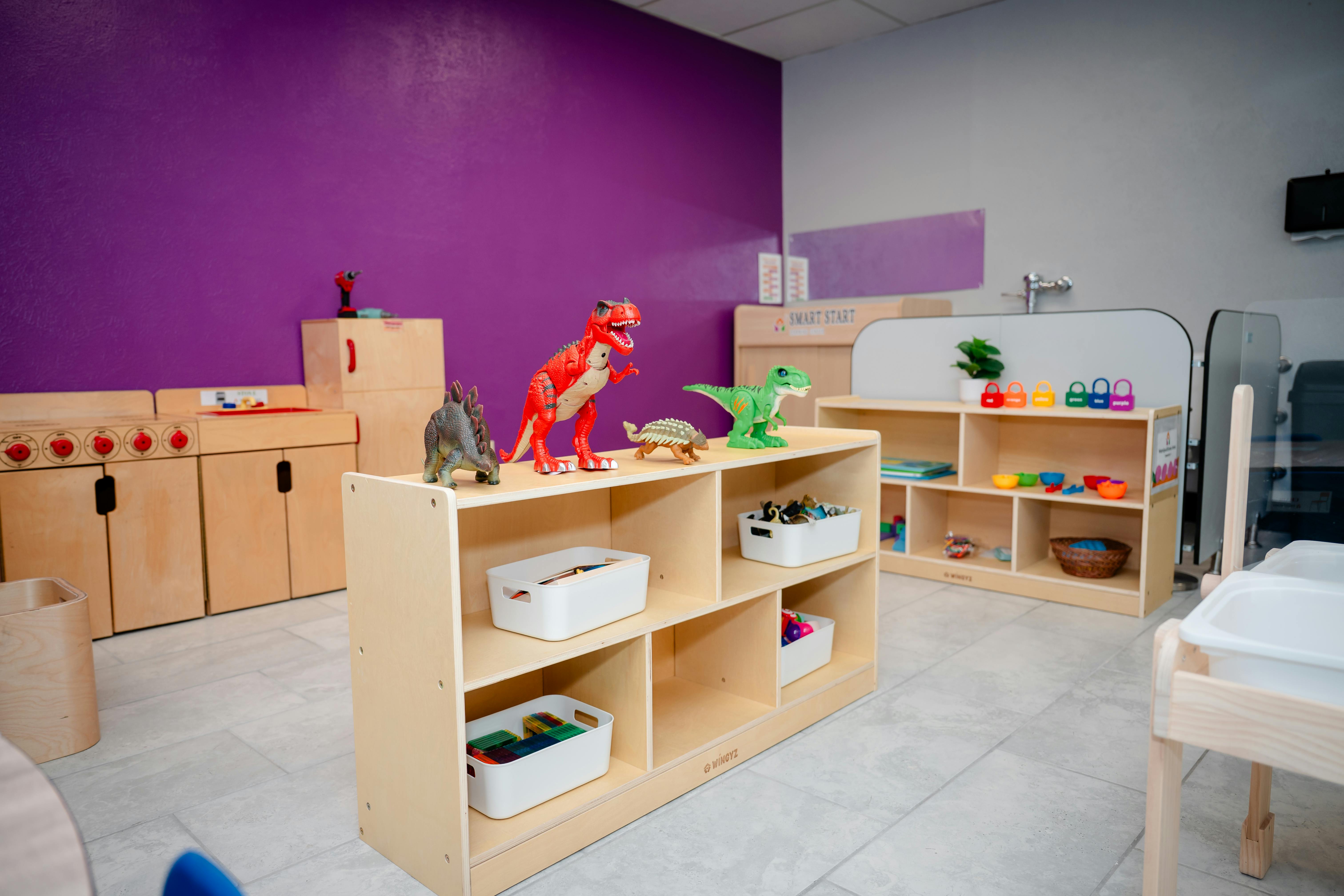 Classroom with wooden shelves, toys, and purple wall
