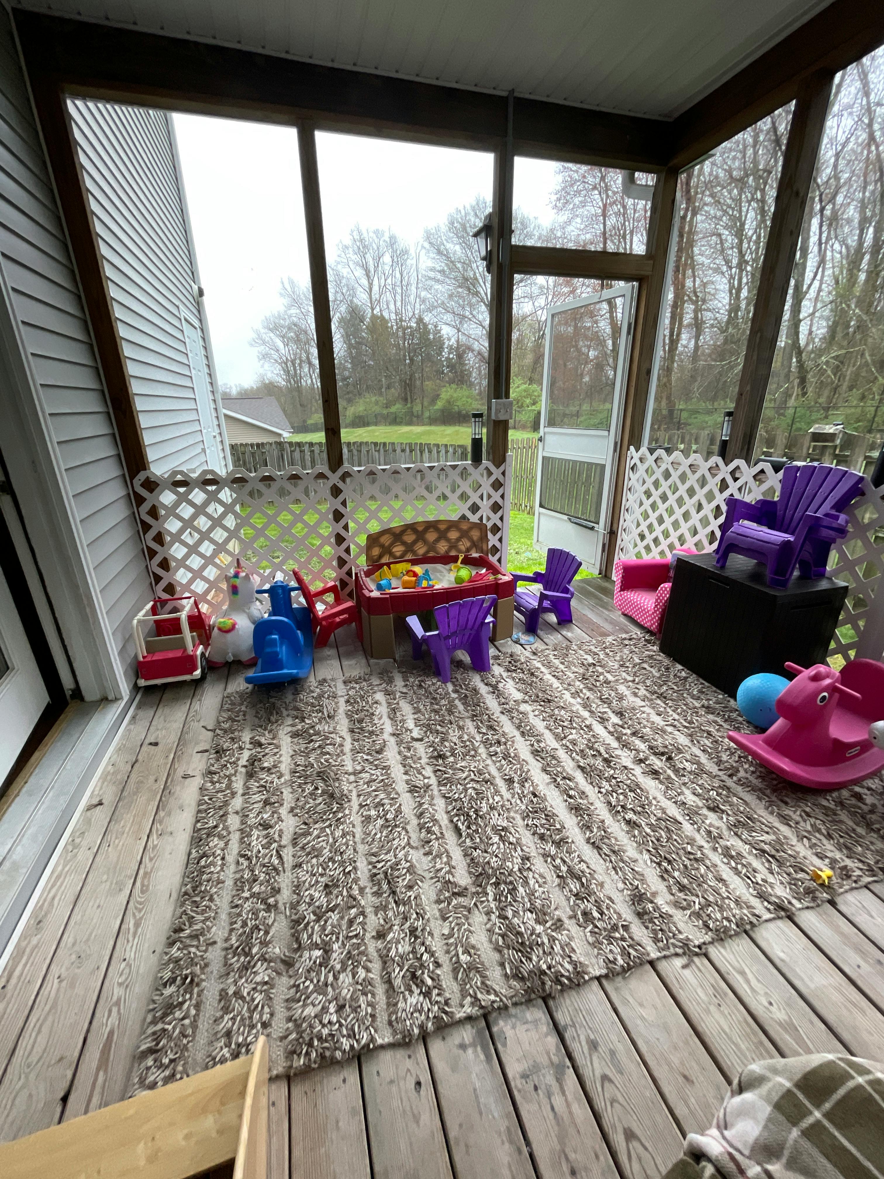 Screened-in porch with a rug and children's play furniture