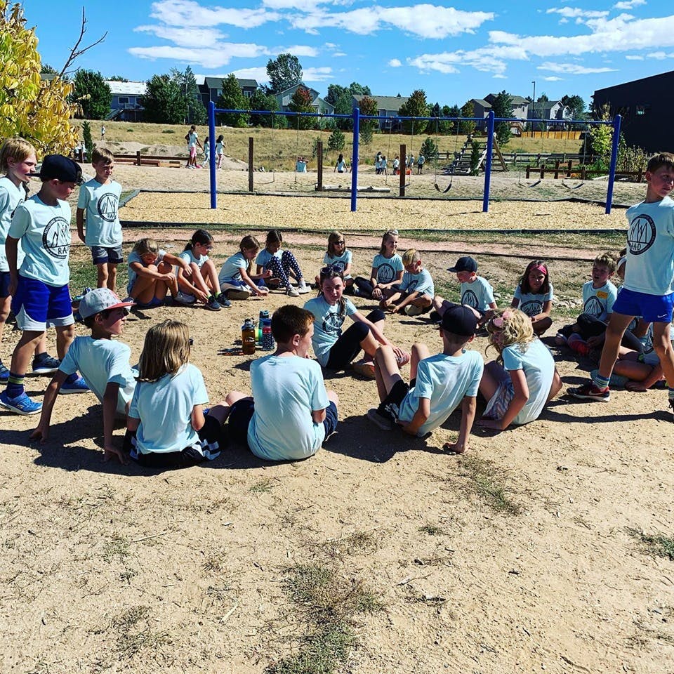 Group of children sitting in a circle on the ground outdoors