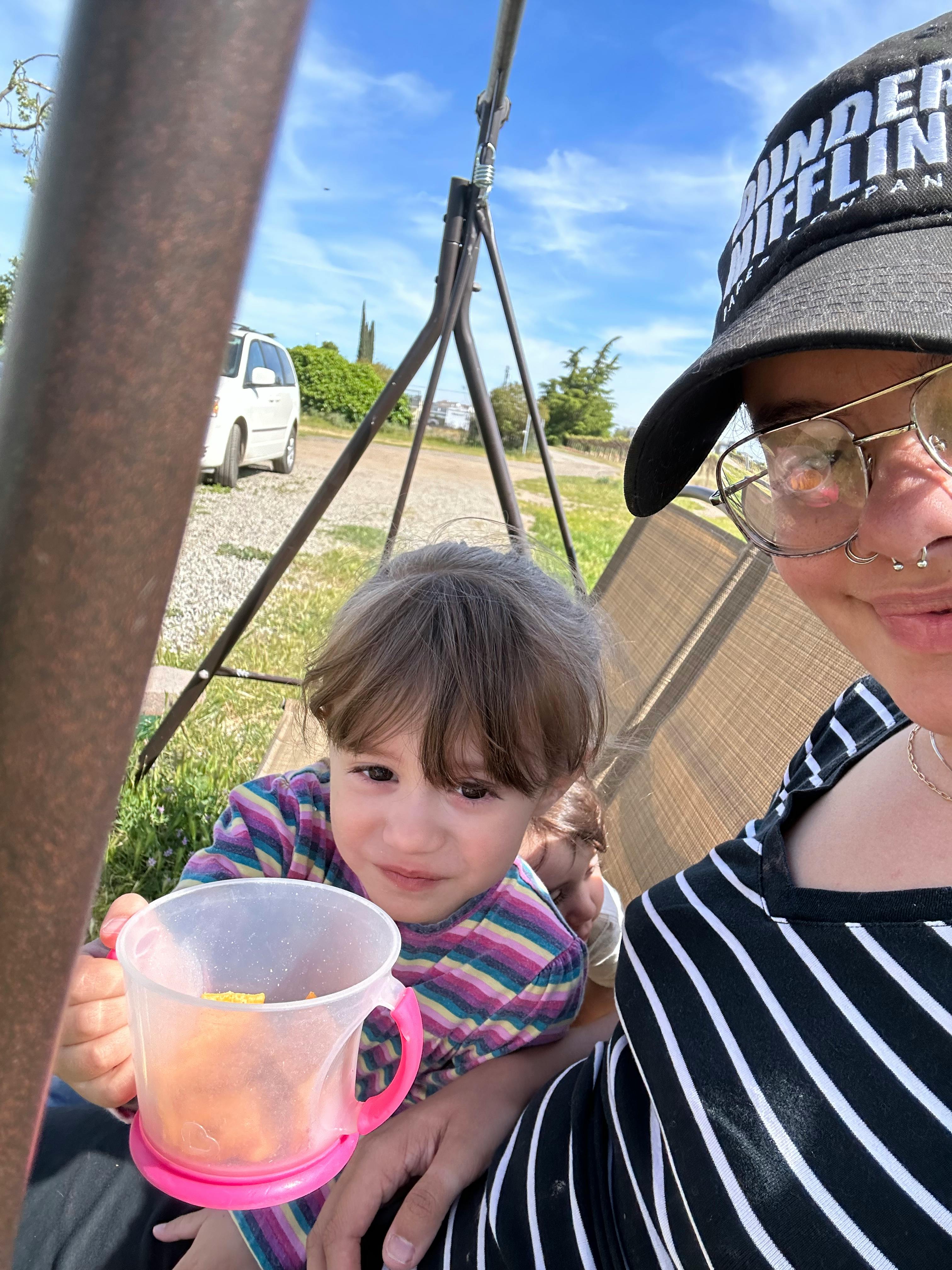 Person in glasses and hat with a child holding a cup