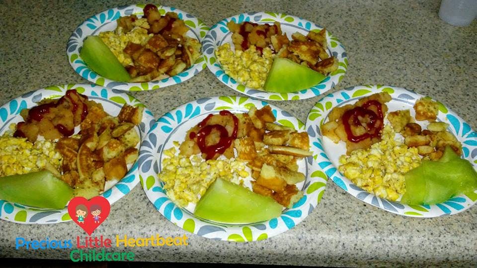 Five paper plates with chicken, corn, and melon slices