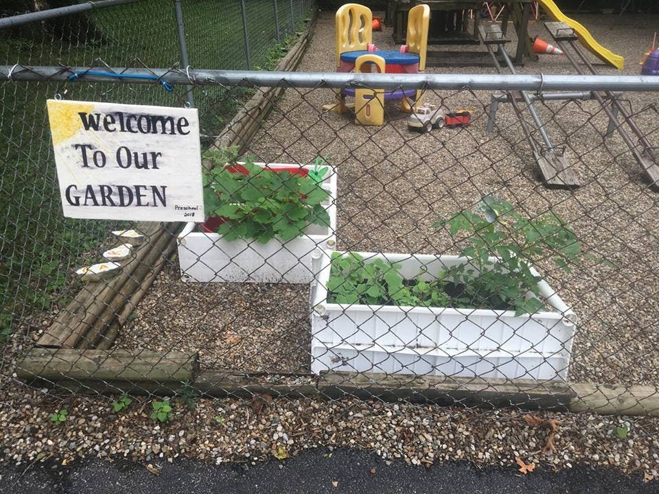 Welcome To Our Garden sign on a fence with two planter boxes