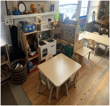 Playroom with small tables and chairs, toy kitchen, and shelves