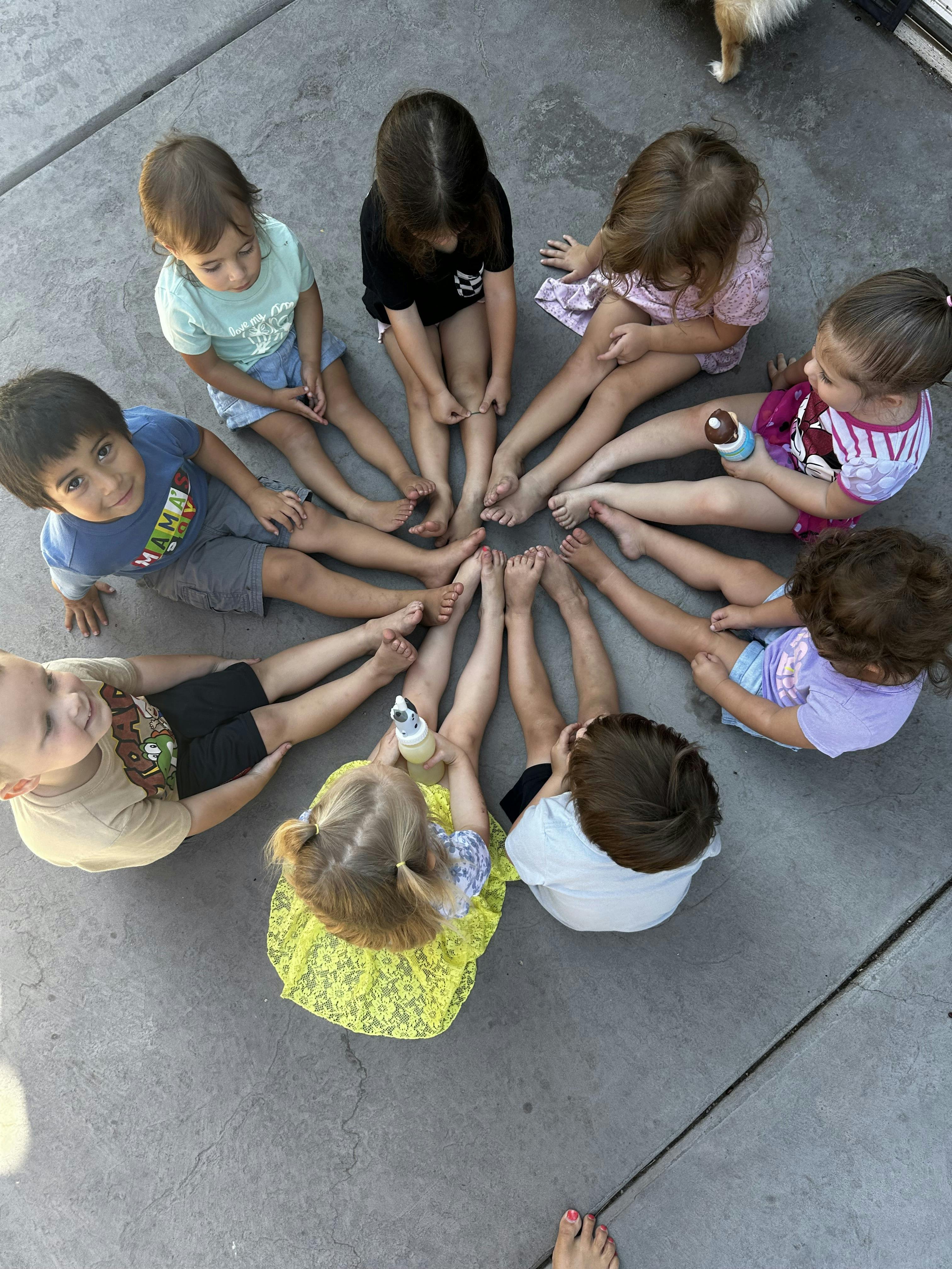 Children sitting in a circle with their feet touching in the center