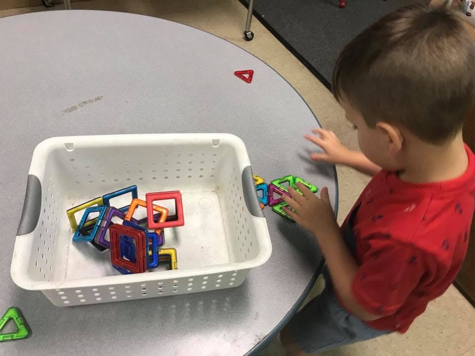 Child playing with colorful magnetic shapes on a table