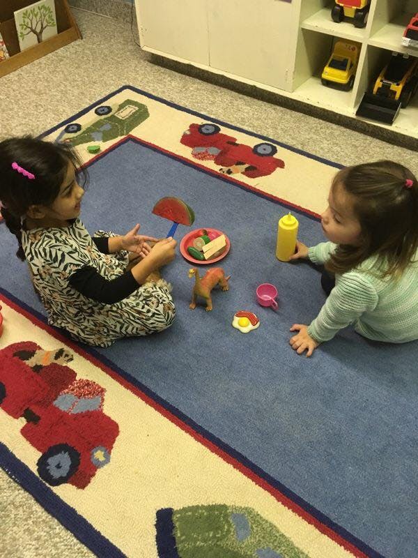 Two children playing with toy food on a rug