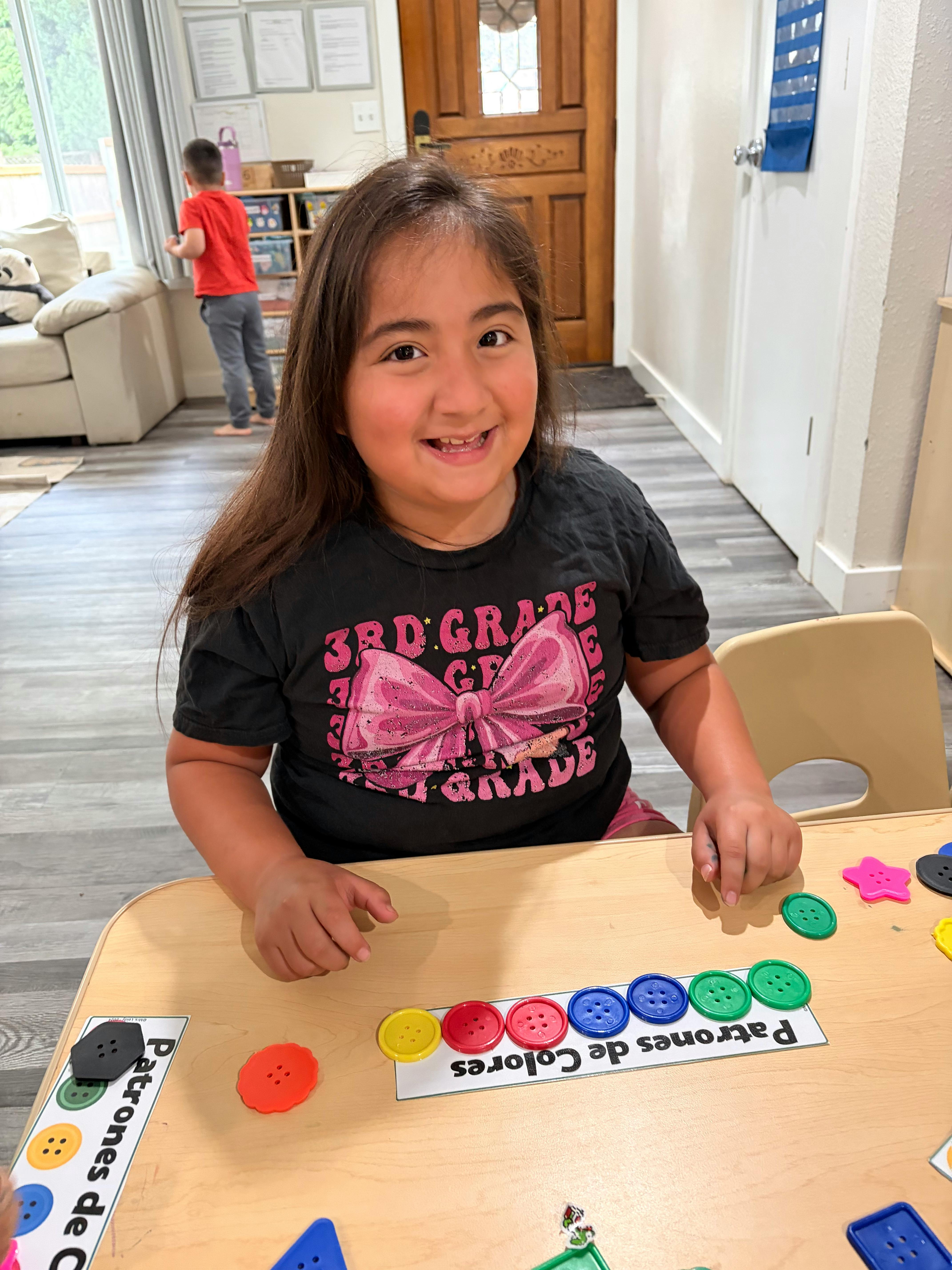 Child sitting at a table arranging colored buttons on a pattern card