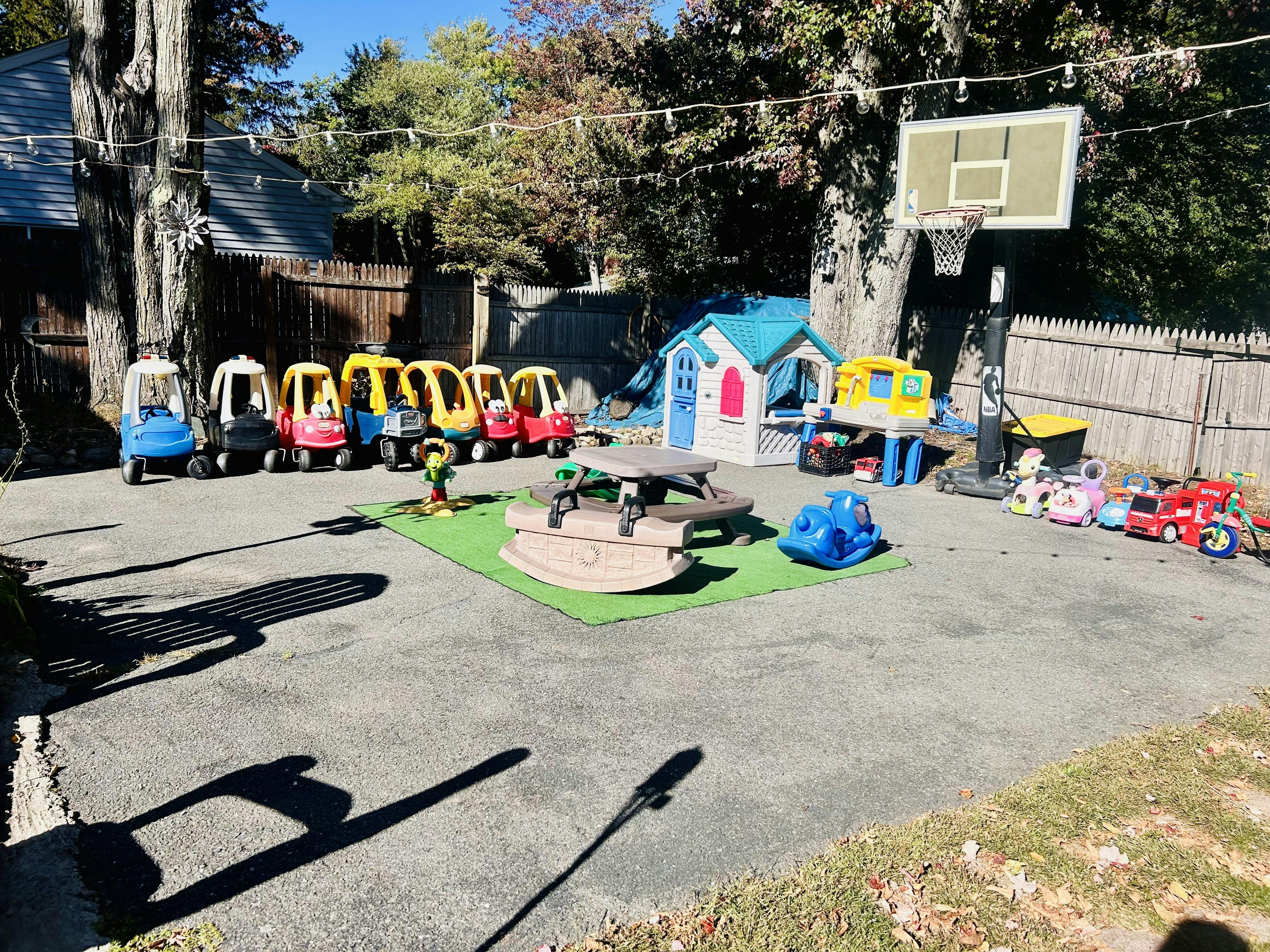 Outdoor play area with toy cars, playhouse, sandbox, and basketball hoop