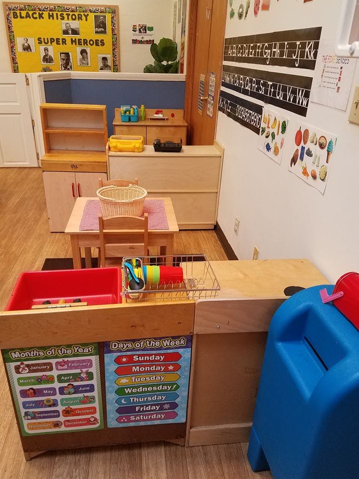 Classroom with play kitchen, small table and chairs, and educational posters