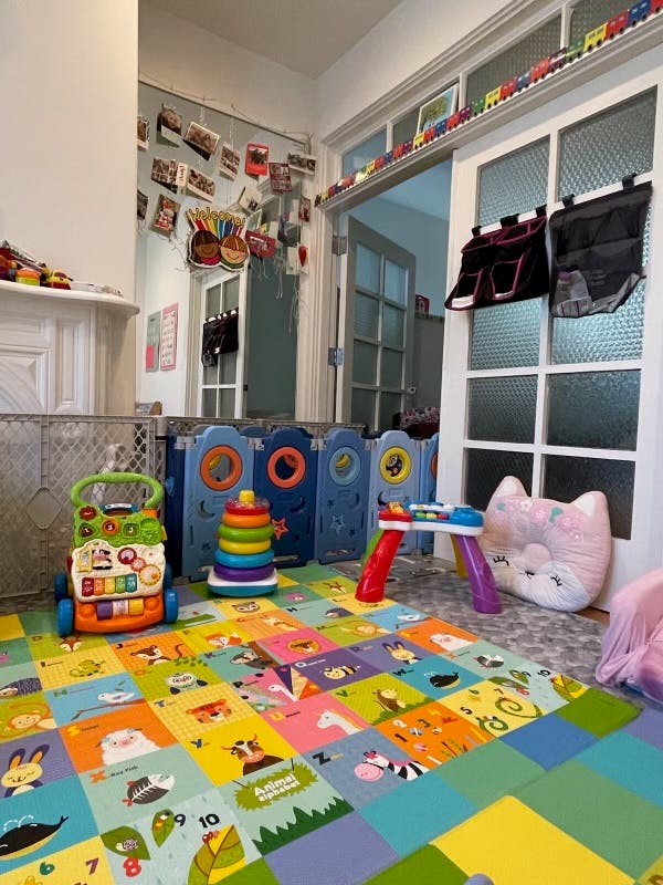 Playroom with colorful floor mats, toys, and a blue playpen