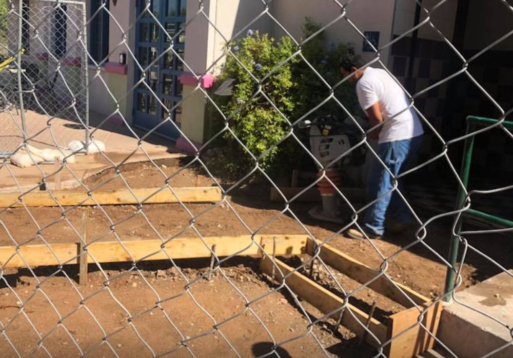 Person working on wooden forms for concrete steps behind a chain link fence
