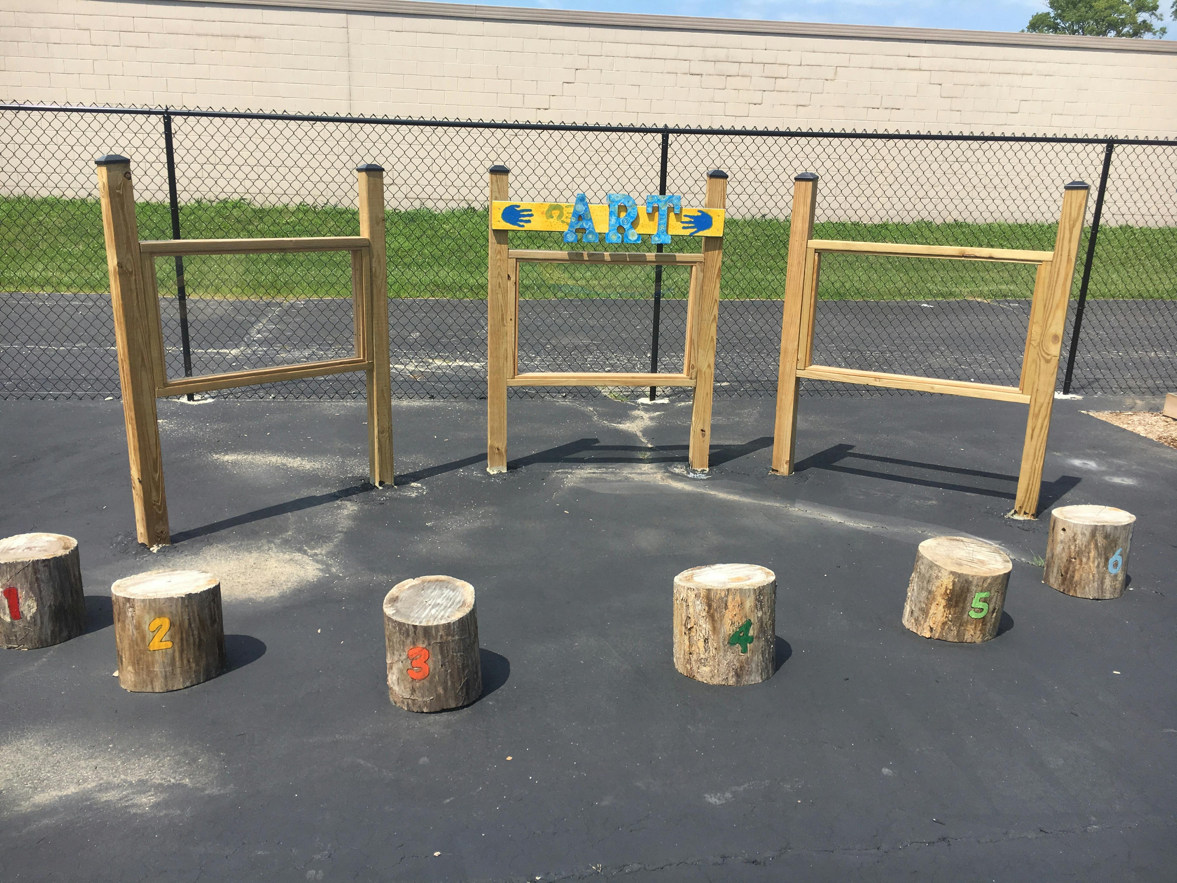 Outdoor play area with wooden climbing structures and tree stump seats