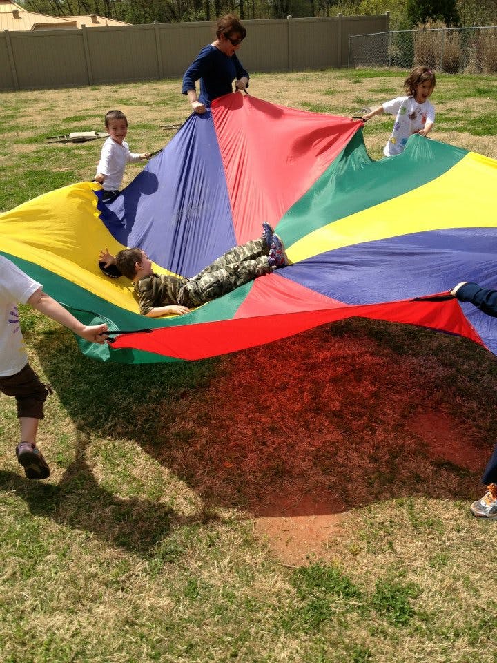 People holding a colorful parachute with a child lying on it