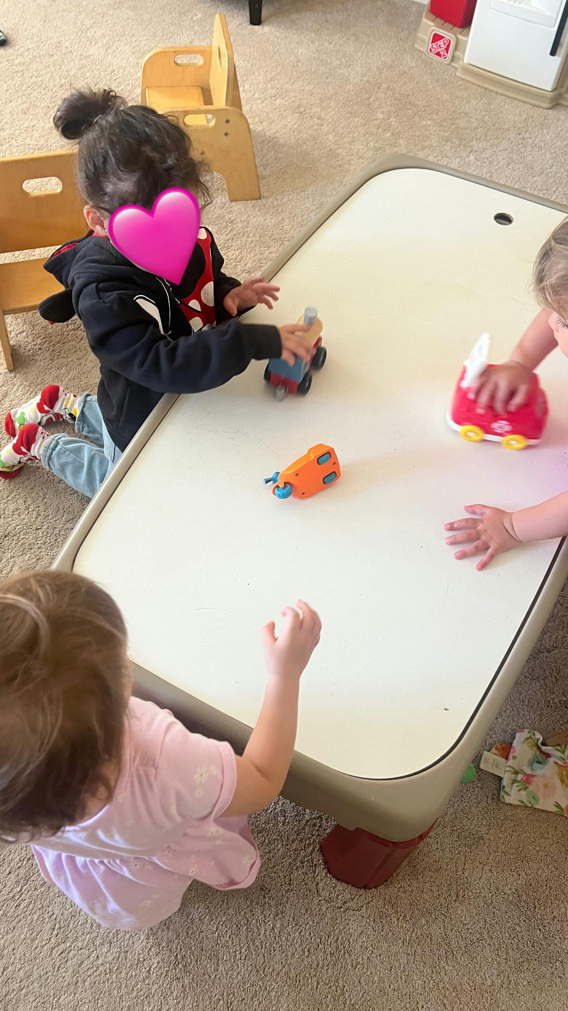 Children playing with toy cars on a table