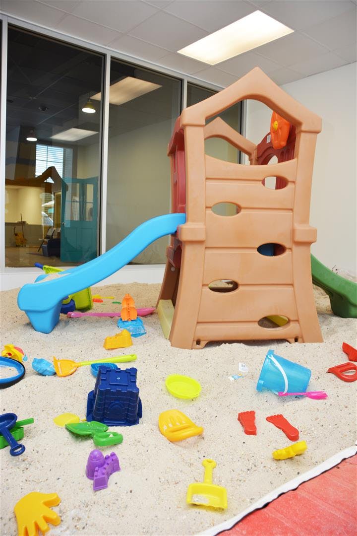 Indoor sandbox with a play structure, slide, and various sand toys