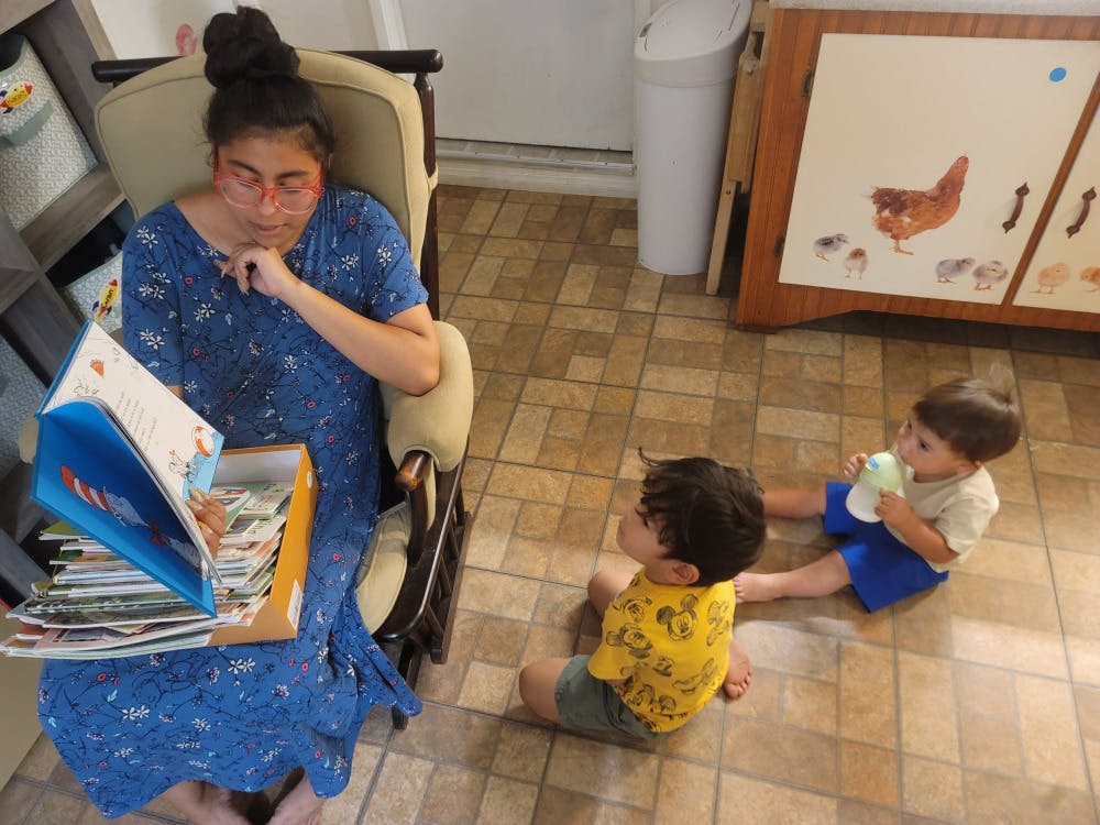 Person reading to two children on the floor