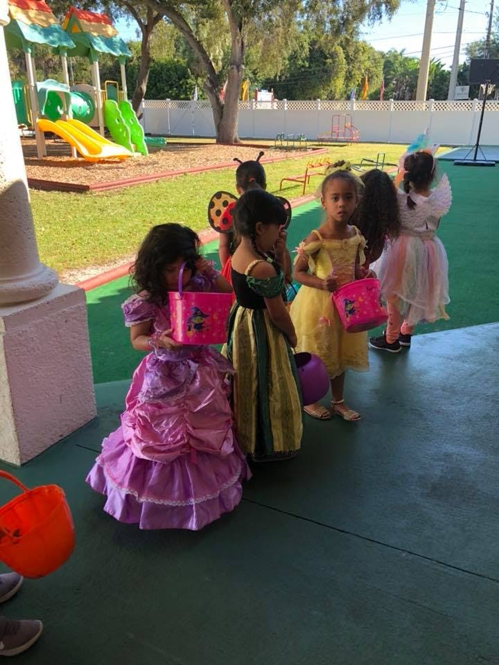 Children in costumes holding buckets on a playground