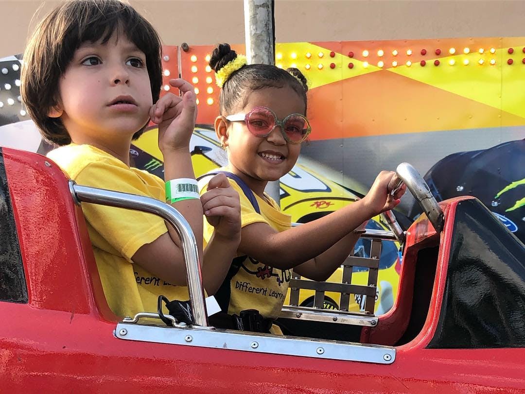 Two children in a red ride car