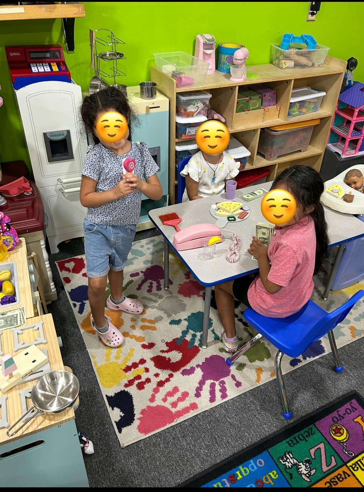 Three children playing at a table in a classroom