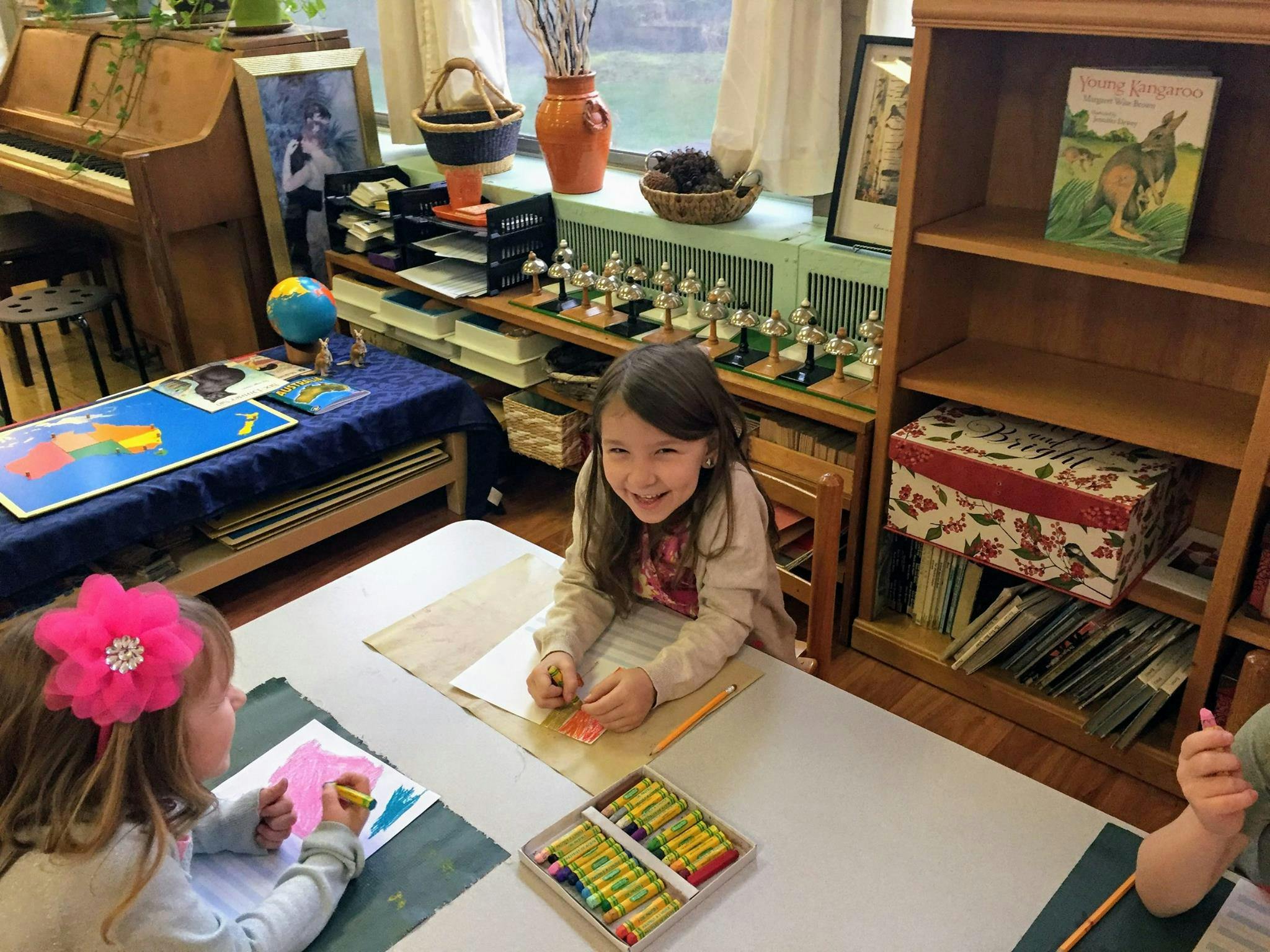 Two children drawing at a table in a classroom