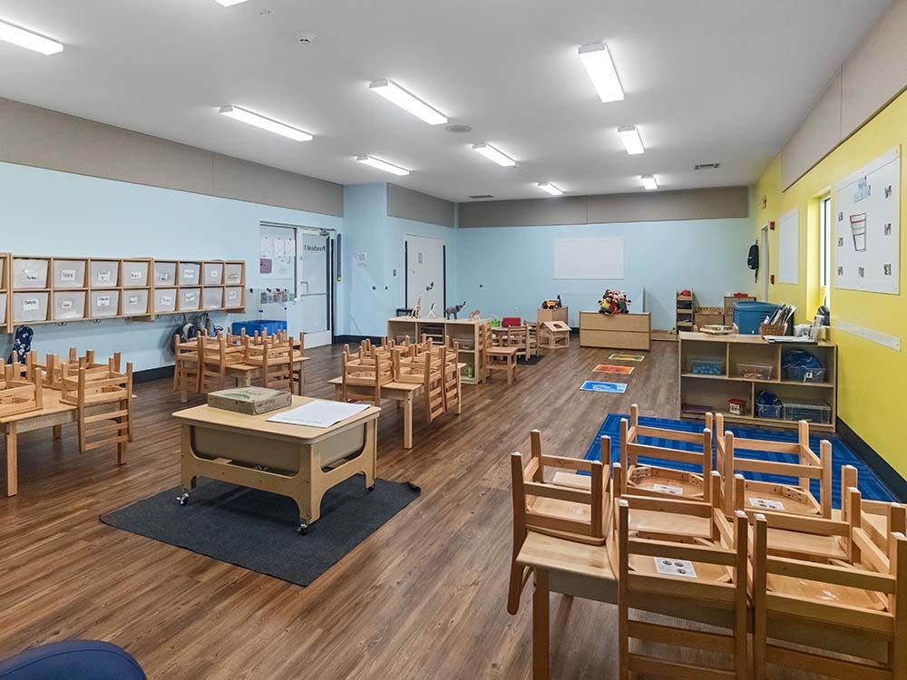 Empty classroom with small tables and chairs stacked upside down