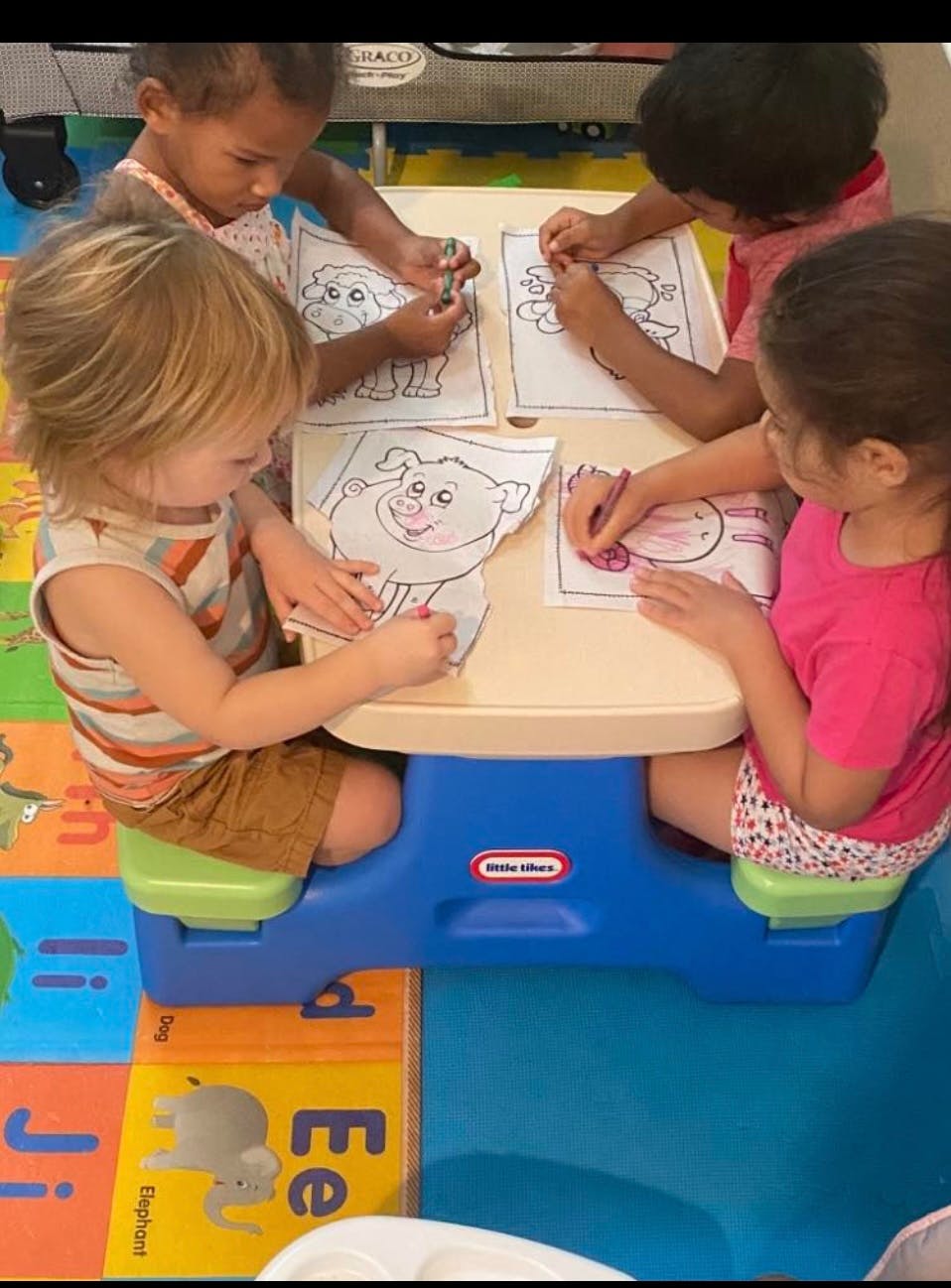 Four children coloring at a small table