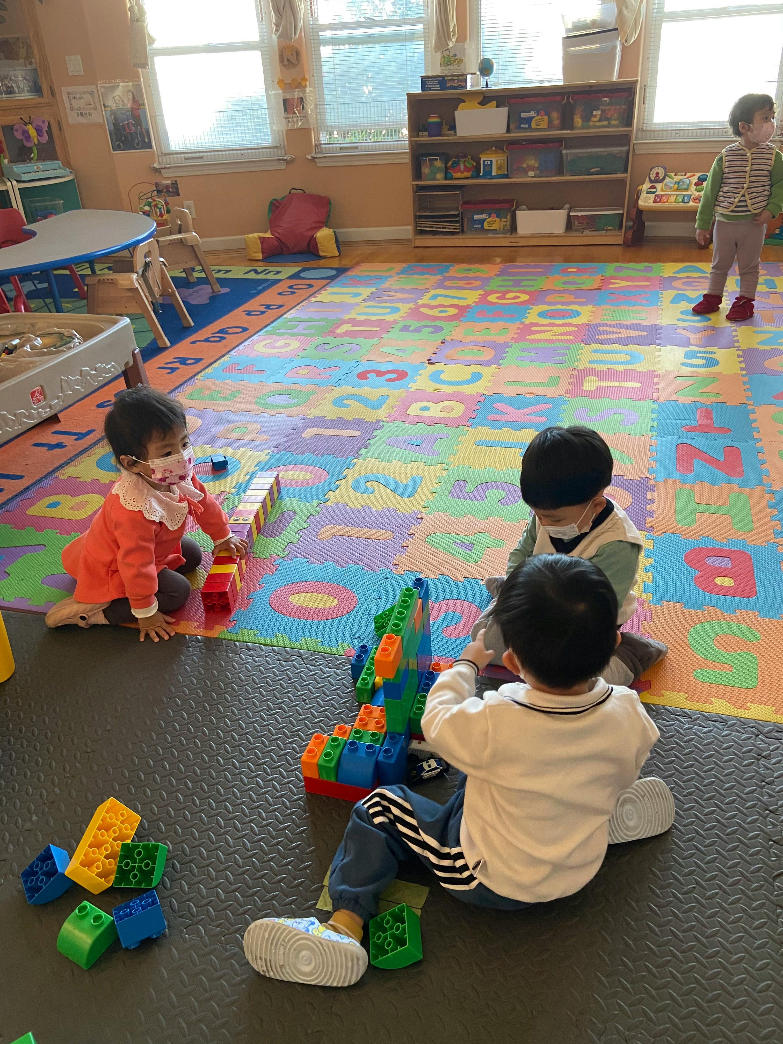 Three children playing with building blocks in a classroom