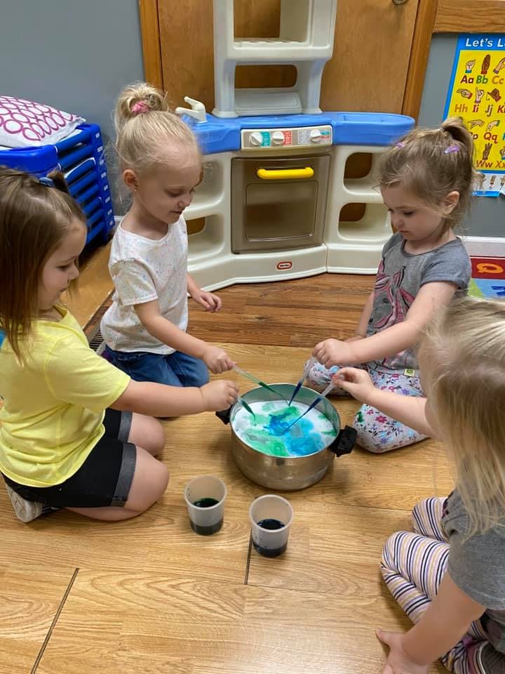 Children mixing colors in a pot on the floor