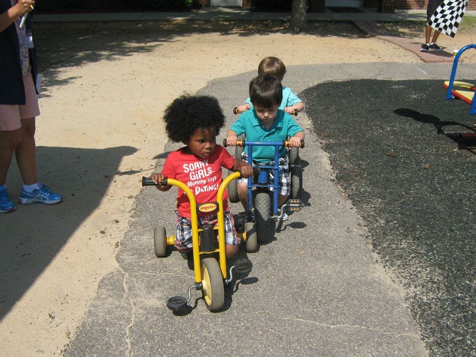 Three children riding tricycles outdoors