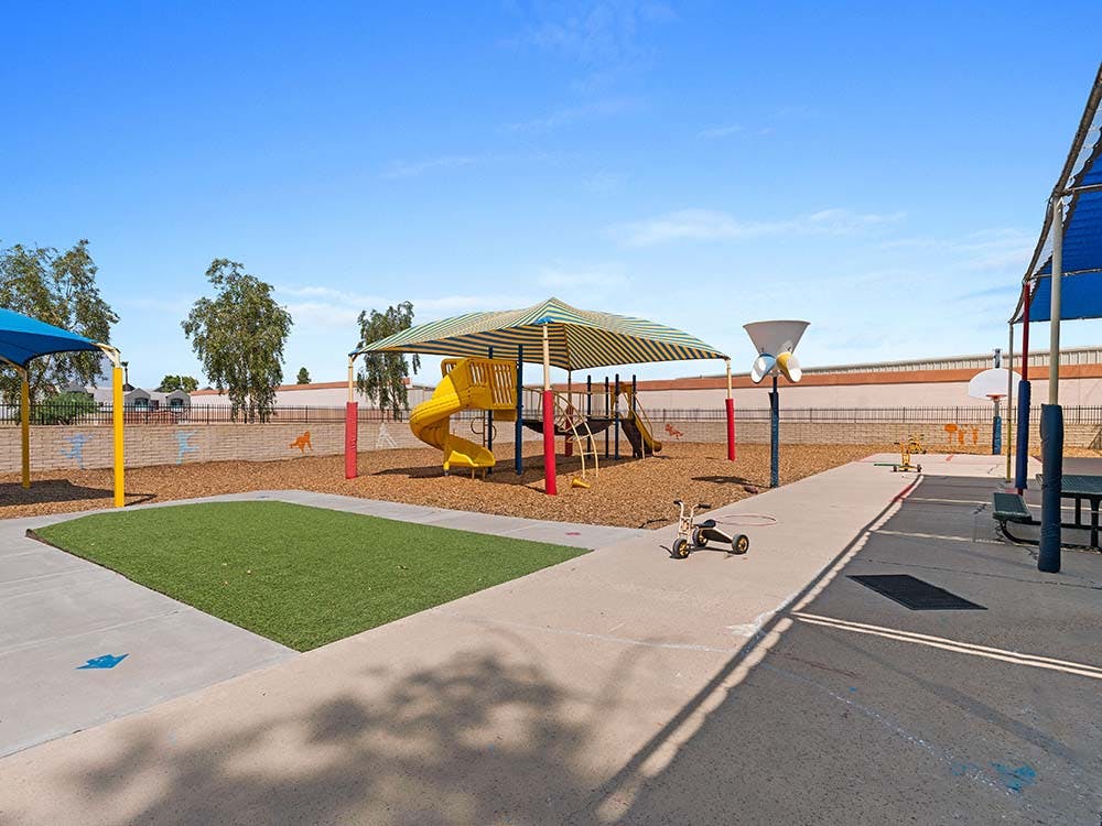 Outdoor playground with slide, artificial turf, and tricycle