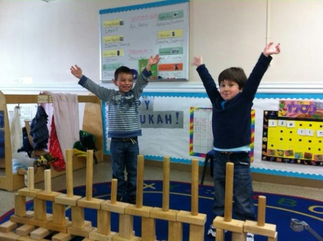 Two children standing with arms raised in a classroom