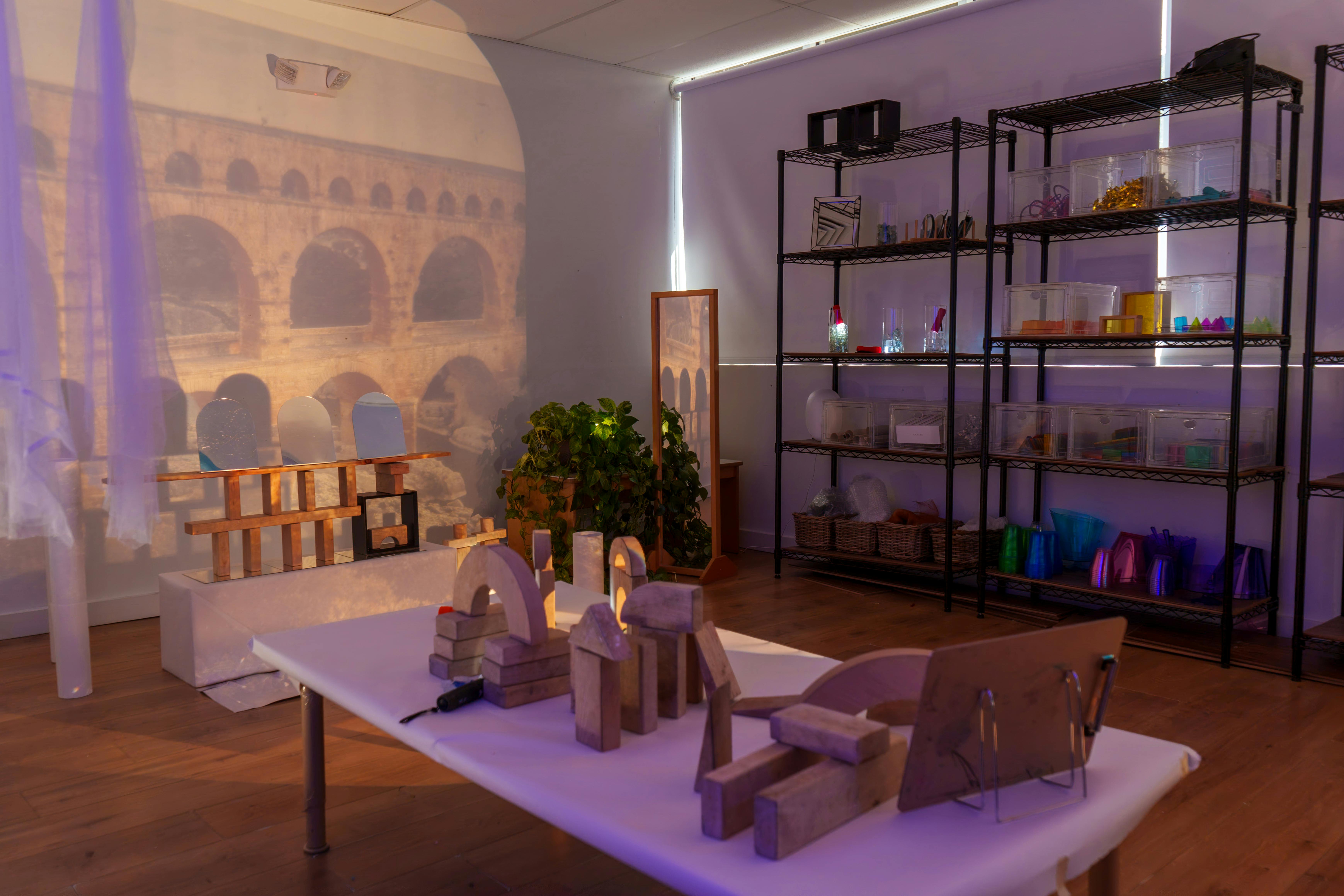 Room with block structures on a table and shelves, historic aqueduct image on wall