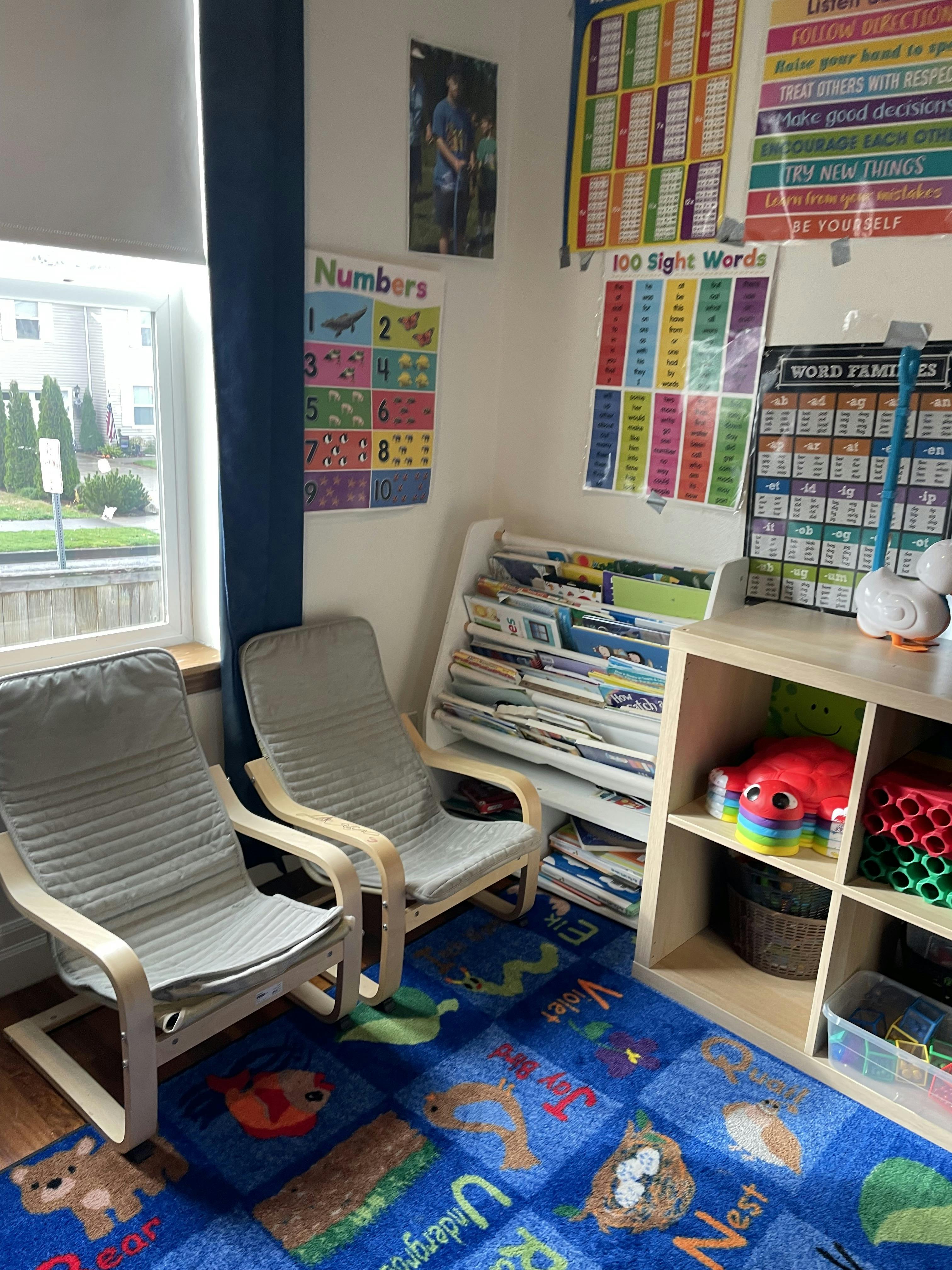 Classroom corner with two chairs, educational wall charts, and a bookshelf