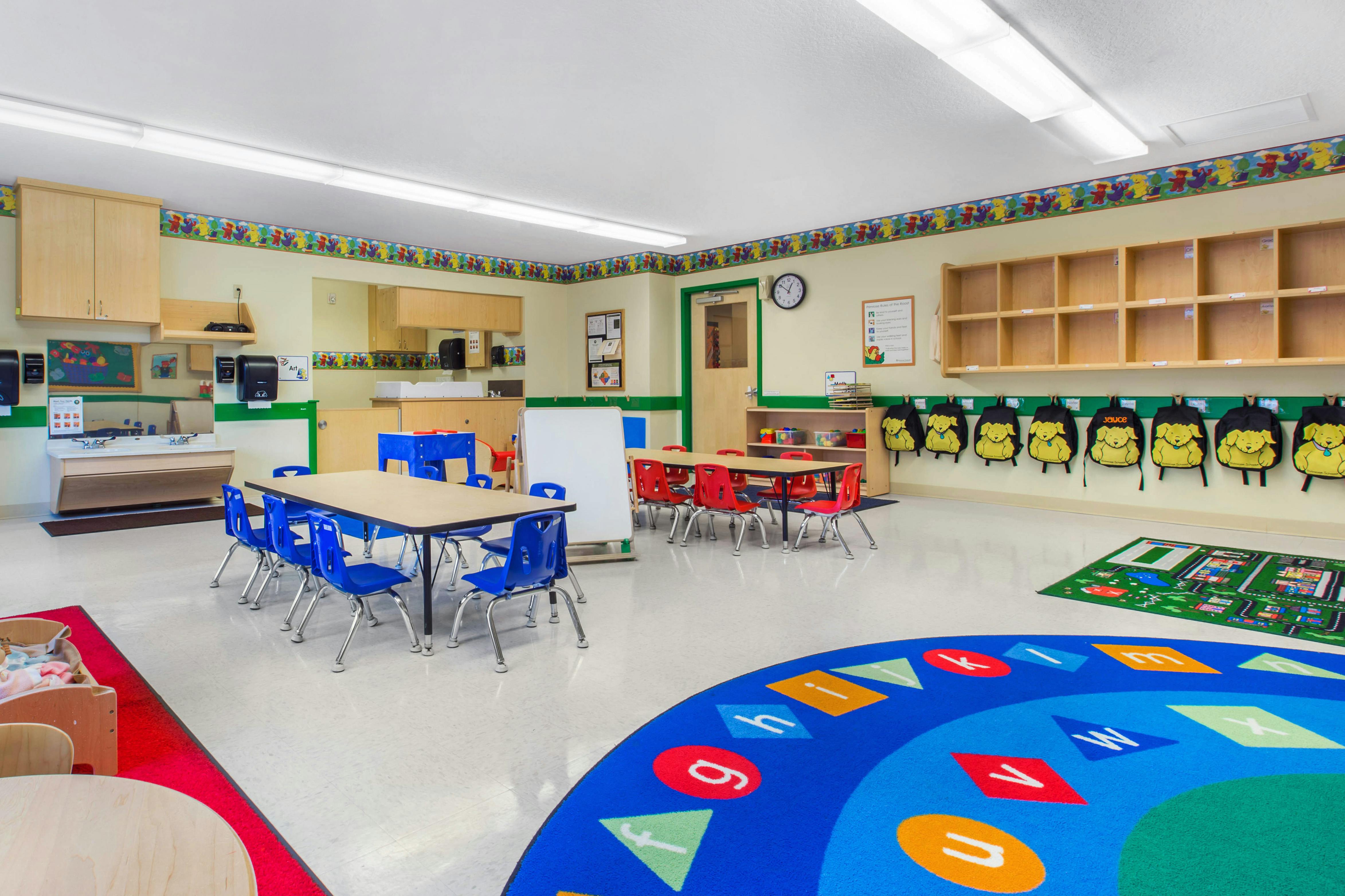 An empty preschool classroom with small tables and chairs