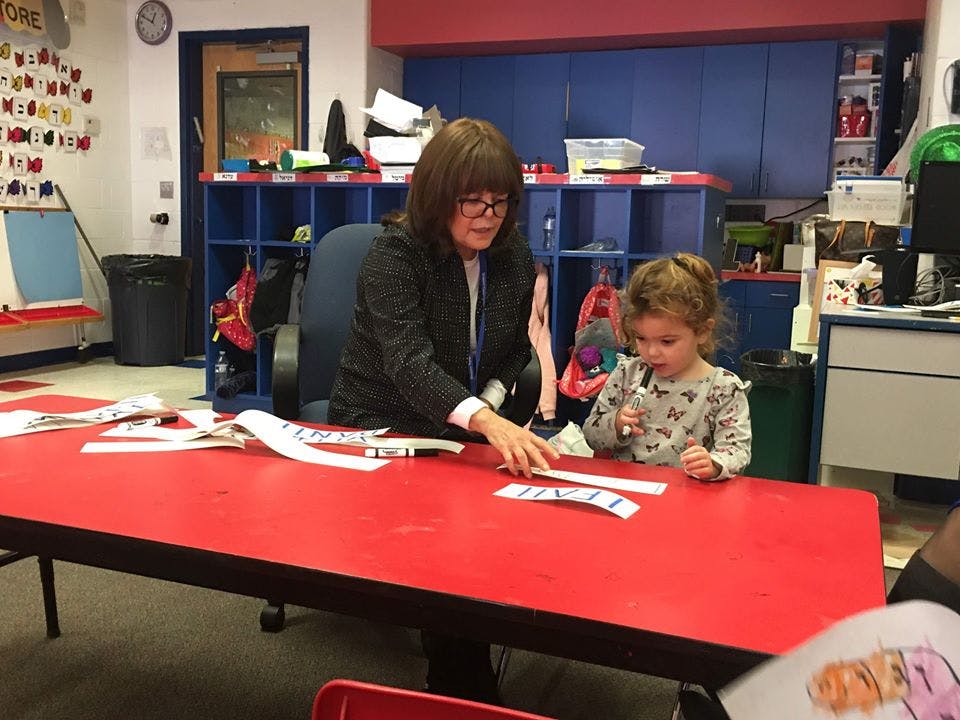 Adult and child at a red table with word strips in a classroom