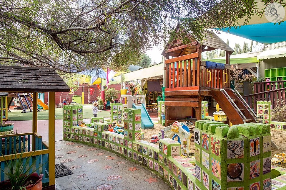 Outdoor playground with wooden play structure, slide, and sandpit