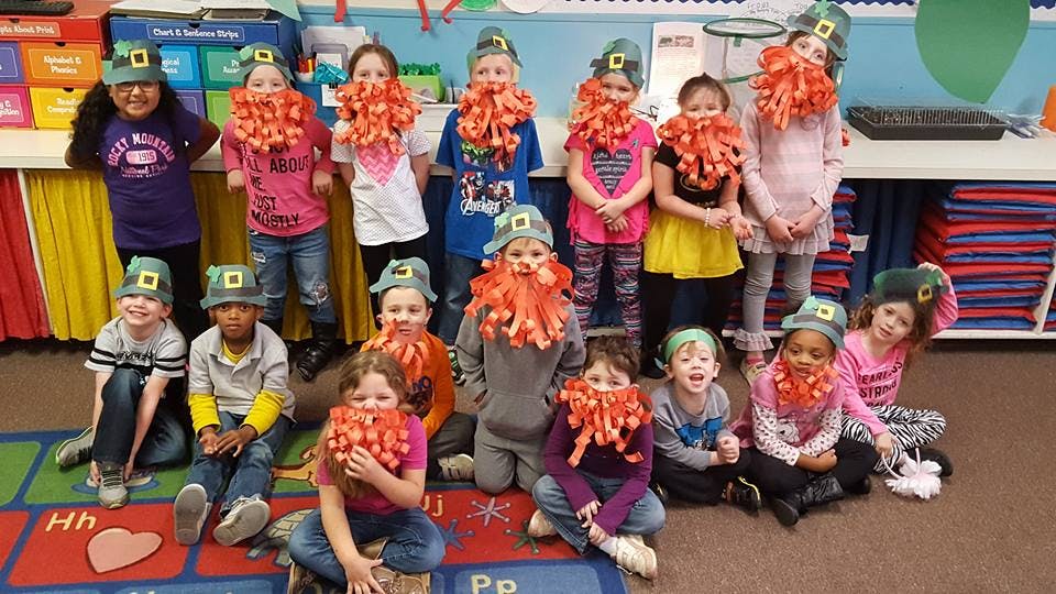 Group of children wearing green hats and orange beards